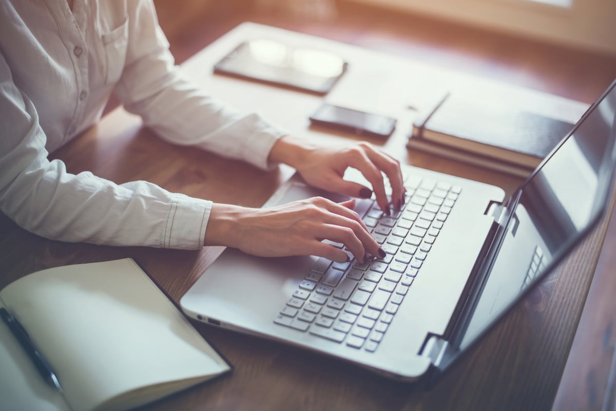 Female working with laptop at home woman's hands on